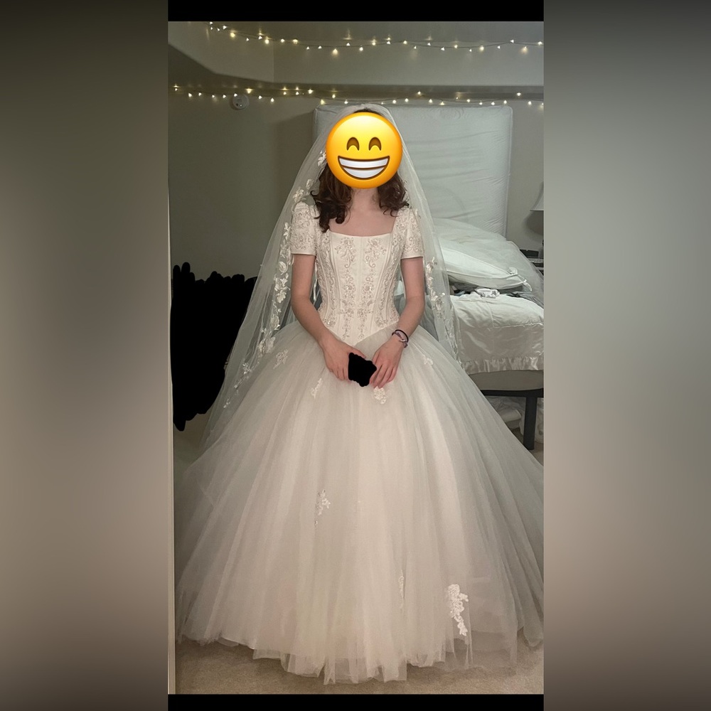 Wedding dress with fitted bodice, basque waist, and full tulle skirt.